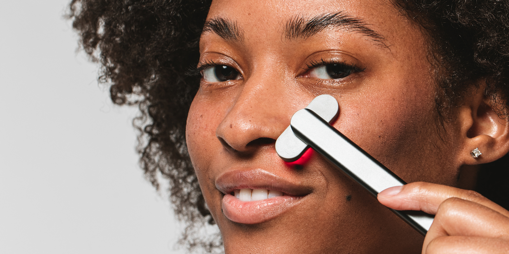 dark-skinned woman uses SolaWave Wand with red light therapy